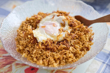 Traditional bowl of Indonesian Nasi Goreng, the country’s national dish, featuring fried rice topped with fried egg, crispy shallots, and sweet soy sauce known as ketjap manis.