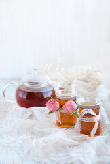Glass tea cups with rose flowers and teapot on table close up. tea in traditional Turkish glass cups. beautiful romantic breakfast for 14 Feb, Valentine's day, birthday, festive date, romantic party