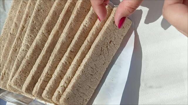 Women's hands take the crisp bread out of the packaging and break them. Low-calorie bread in the diet during the diet.