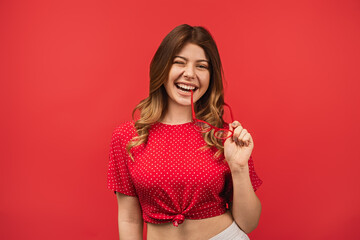 Bright and energetic studio portrait of a young woman wearing a red polka dot shirt, smiling with a...