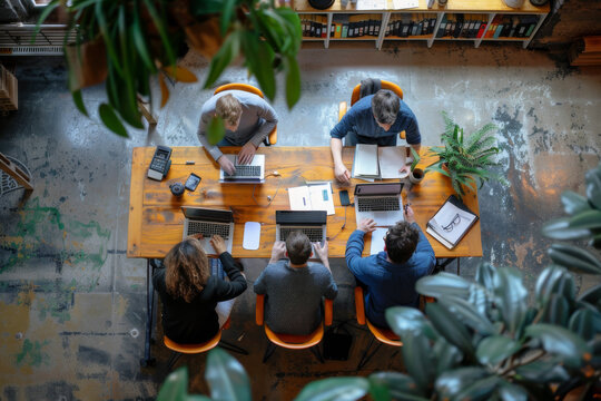 Creative team working together at a rustic wooden table in a modern office.