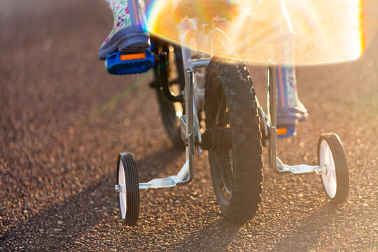 child riding bike with training wheels on quiet suburban street