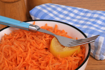 Carottes râpées servies dans une assiette avec une fourchette et une rondelle de citron en gros...