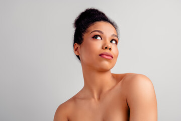 Obraz premium Young beautiful woman with natural skin and stylish bun posing gracefully on a soft beige background