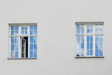 Windows with muntins reflecting blue sky on bright building facade, architectural detail showing symmetry, light, and classic window design elements
