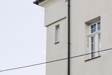 Windows with muntins reflecting blue sky on bright building facade, architectural detail showing symmetry, light, and classic window design elements