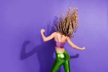 Young woman dancing energetically against a vibrant purple backdrop, embodying the spirit of retro...