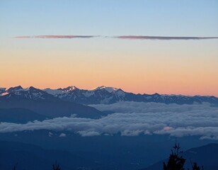 Mountain range at sunrise, clouds below