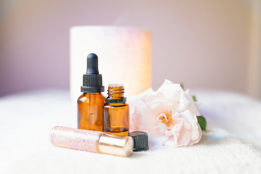 Collection of amber essential oil bottles with fresh rose and diffuser