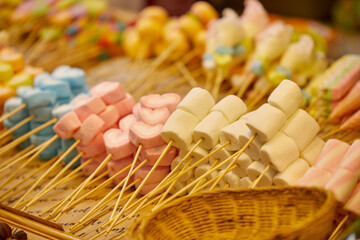 Multicolored of skewers marshmallow and candy at night market 