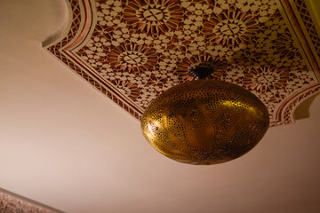 Typical Arabic lamp from Marrakech hanging with symmetrical patterns on ceiling