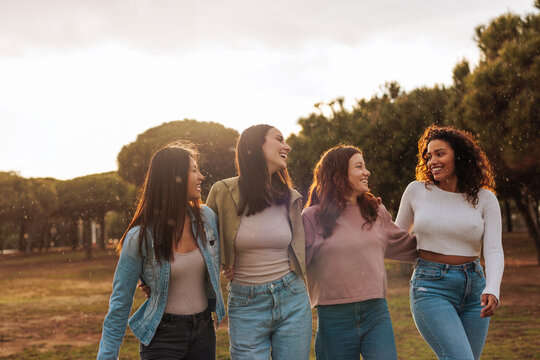 Happy friends laughing and walking in the field