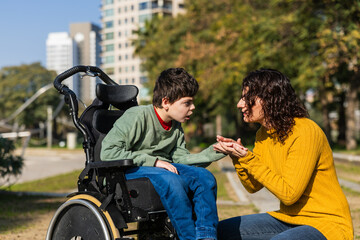 Mother comforting her son in a wheelchair in a city park