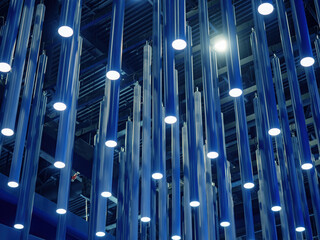 Fototapeta premium Modern ceiling with multiple cylindrical LED light fixtures hanging in a geometric arrangement, part of interior lighting design – Architecture, Lighting Design.
