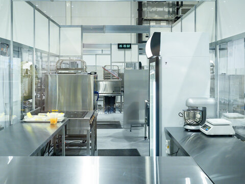 Modern industrial kitchen with stainless steel equipment, worktables, refrigerator, mixer, and scale, designed for food production – Food Industry, Commercial Kitchen.