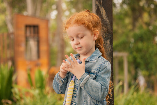 Outdoor portrait of preschool age girl counting fingers on her hand at kindergarten - Powered by Adobe