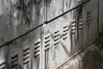 Weathered metal surface with ventilation slots and exposed wires