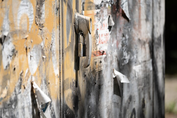 Old weathered metal door with padlock and peeling paint