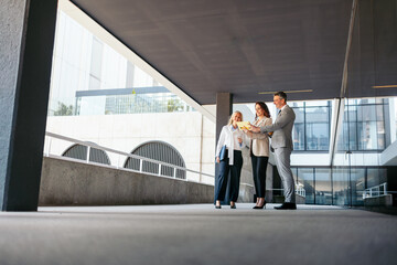 Business team reviewing contract terms on digital tablet in modern office building. View from below.