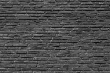 The black wall is made of uneven black gloomy stones. Abstract dramatic background.