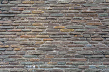 The wall of the castle is made of uneven, flat stones of various dark shades. Abstract dramatic background.