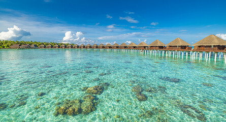 Stunning Maldives water villas wooden pier over turquoise sea bay picturesque summer landscape. Amazing luxury travel tropical beach vacations. Honeymoon tourism destination paradise, sunny blue sky