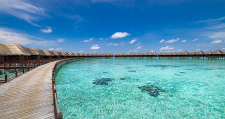 Stunning Maldives water villas wooden pier over turquoise sea bay picturesque summer landscape. Amazing luxury travel tropical beach vacations. Honeymoon tourism destination paradise, sunny blue sky