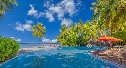 Luxury infinity swimming pool in tropical hotel resort. Palm trees poolside lounge chairs umbrellas. Leisure exotic travel destination, summer tourism beach holiday. Stunning sea sand beach landscape