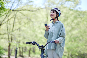 自然の中でサイクリングを楽しむスマートフォンを持った日本人女性