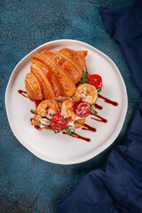 Delicious croissant sandwich filled with grilled shrimp, fresh arugula, cherry tomatoes and cream cheese. Topped with balsamic glaze and served on a white plate