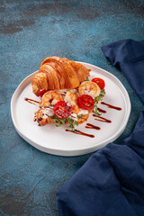 Delicious croissant sandwich filled with grilled shrimp, fresh arugula, cherry tomatoes and cream cheese. Topped with balsamic glaze and served on a white plate