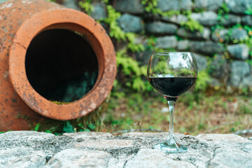 Glass of Red Wine with Traditional Georgian Qvevri in Rustic Setting