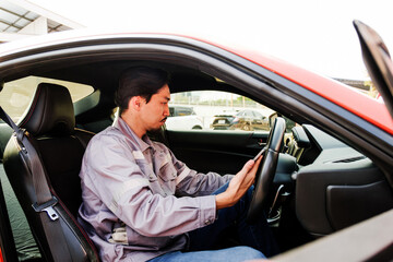 Auto technician inspects vehicle dashboard inside a red car at a service center, showcasing professional automotive diagnostics, maintenance expertise, and modern car repair industry standards.