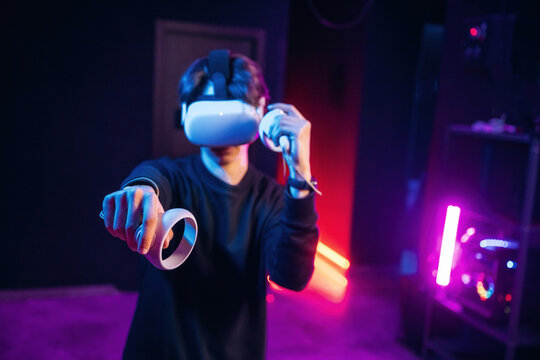 Interacting with game by using controllers. Young man is in virtual reality glasses indoors