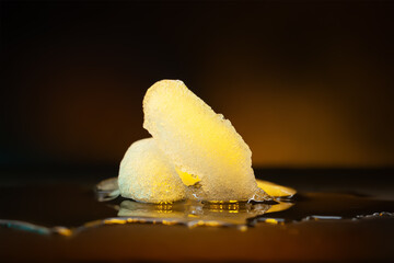 Ice melting. Melting ice chunks on dark. Yellow backlight