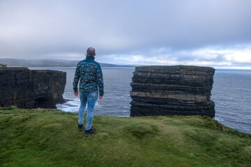 Person looking at the cliffs of Downpatrick Head with the Atlantic Ocean Co. Mayo, Connacht...