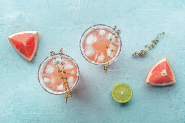 Salty Dog cocktail with fresh grapefruit juice, lime juice, and thyme, shot from the top with fruit slices