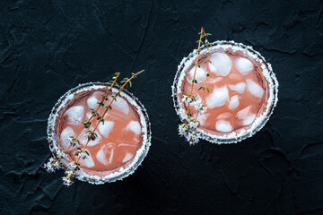 Salty Dog cocktail with fresh grapefruit juice, lime juice, and thyme, overhead flat lay shot on a black slate background