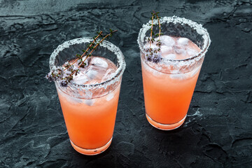 Salty Dog cocktail with fresh grapefruit juice, lime juice, and thyme, on a black slate background