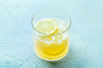 A glass of lemonade, a mocktail with lemon juice, on a blue background, summer cold drink