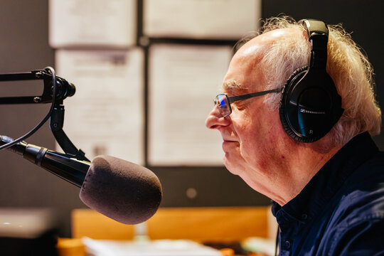 An elderly caucasian man DJs and presents his music show on live radio in Castlemaine, Australia