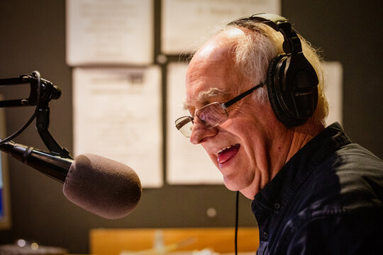 An elderly caucasian man DJs and presents his music show on live radio in Castlemaine, Australia