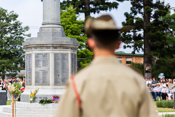ANZAC day memorial service with focus on cenotaph and blurred soldier in foreground