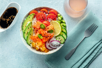 Poke bowl with salmon. Hawaiian salad with rice, fish, tomato, and avocado. Healthy diet. Shot from the top with soy sauce