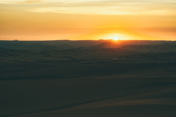 Golden sunset over the vast dunes of the Ica Desert near Huacachina, Peru.
