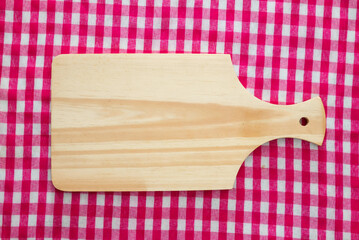 Wooden cutting board with red checkered tablecloth background