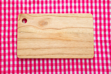 Wooden cutting board with red checkered tablecloth background