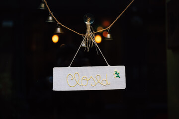 Closed sign hanging on glass door with bells and string, showing business temporarily unavailable