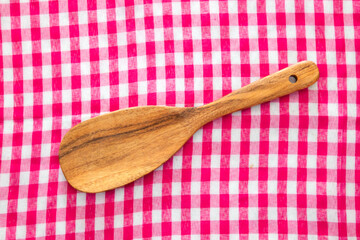 Wooden spoon on red checkered tablecloth background