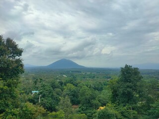 A peaceful morning sky with soft blue hues and gentle clouds above a green forest. Ideal for background use, graphic design, presentations, and travel content.